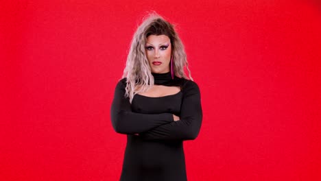drag performer posing with arms crossed on red background