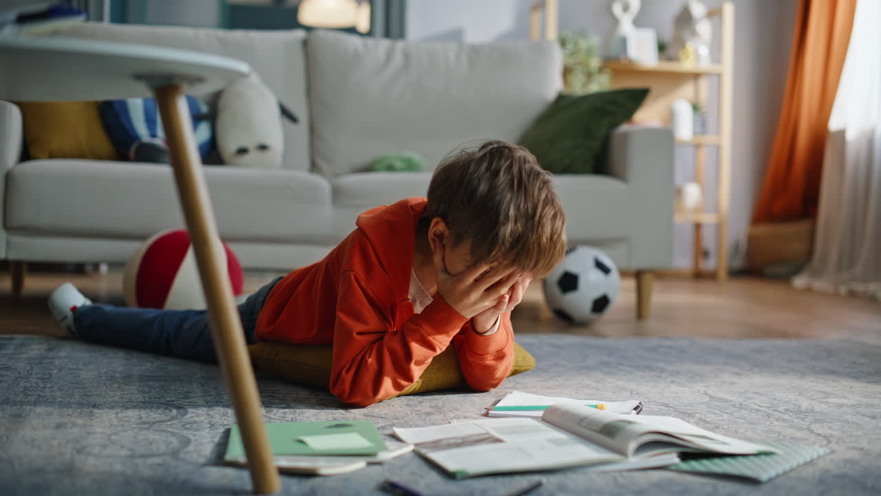 Elementary school student studying home lying floor closeup. Boy pupil writing