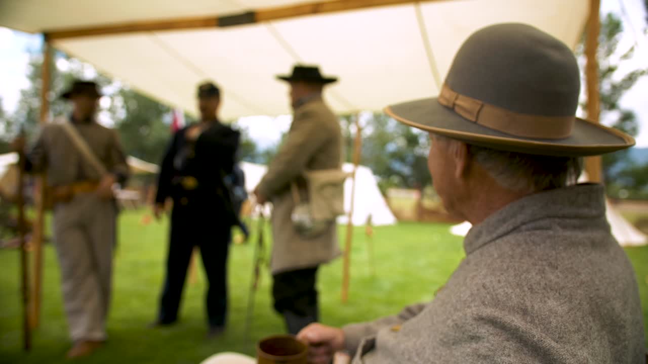 Civil War Soldiers standing in a tent talking and having a drink from a cup