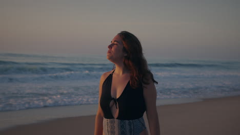 girl-slowly-walking-by-the-sea-at-golden-hour-looking-at-the-sunset