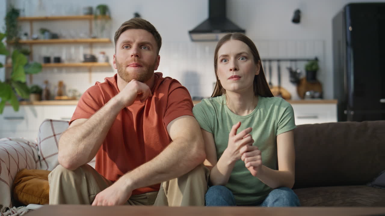 Family pair watching sport championship on TV at sofa closeup. Emotional spouses