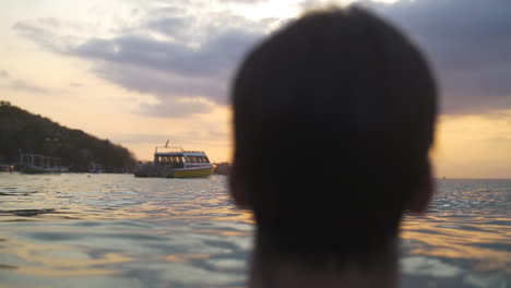 hombre parado en el agua junto al océano mirando la puesta de sol en el paraíso tropical