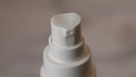 dosing canister of cosmetic cream spinning on cream background