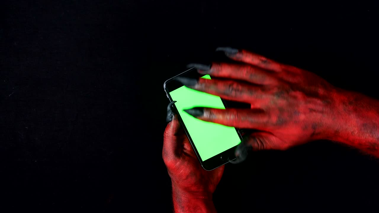 la mano del diablo usa un teléfono inteligente con una pantalla verde. 50 fps