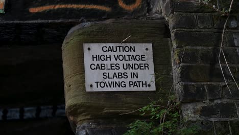 Caution,-there-are-high-voltage-cables-under-slabs-in-the-towing-path,-Camden,-London,-United-Kingdom
