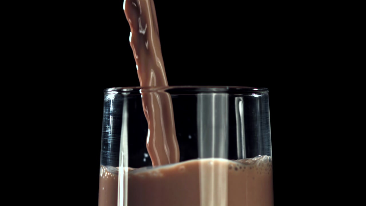 Versamento al rallentatore di latte al cioccolato in un bicchiere