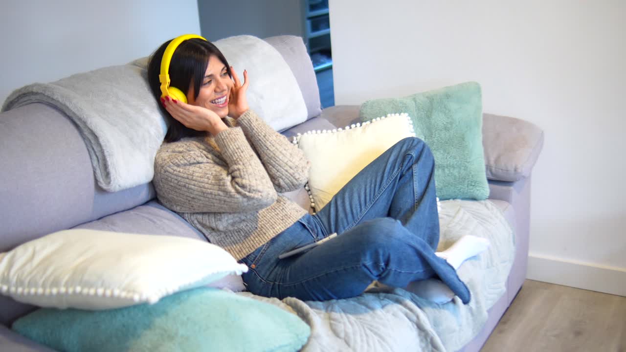 여성이 헤드폰으로 소파에서 휴식을 취하고 있습니다.