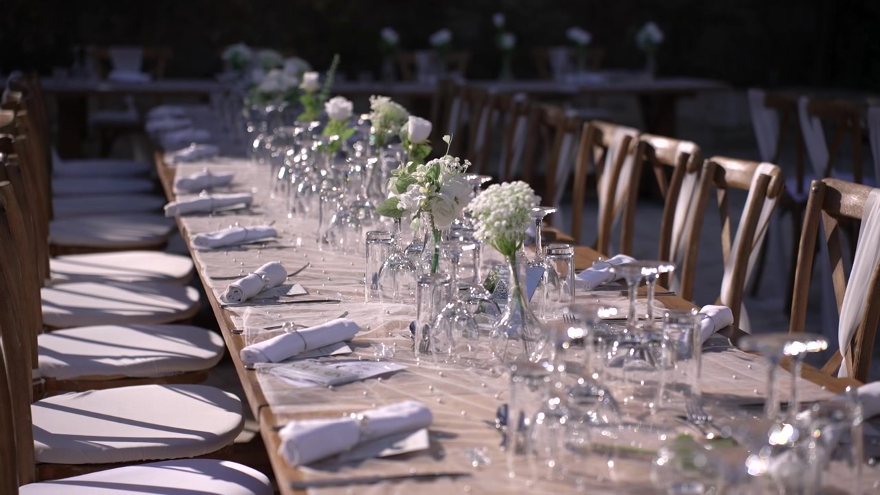 Tavoli sono disposti all'aperto con fiori bianchi e bicchieri per un evento. Gli ospiti gusteranno i loro pasti in questo splendido giardino immerso nella natura