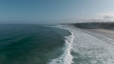 Aerial-view-of-waves-breaking-during-the-world-bodyboard-competition-on-a-sunny-day-at-Praia-Grande-in-Sintra