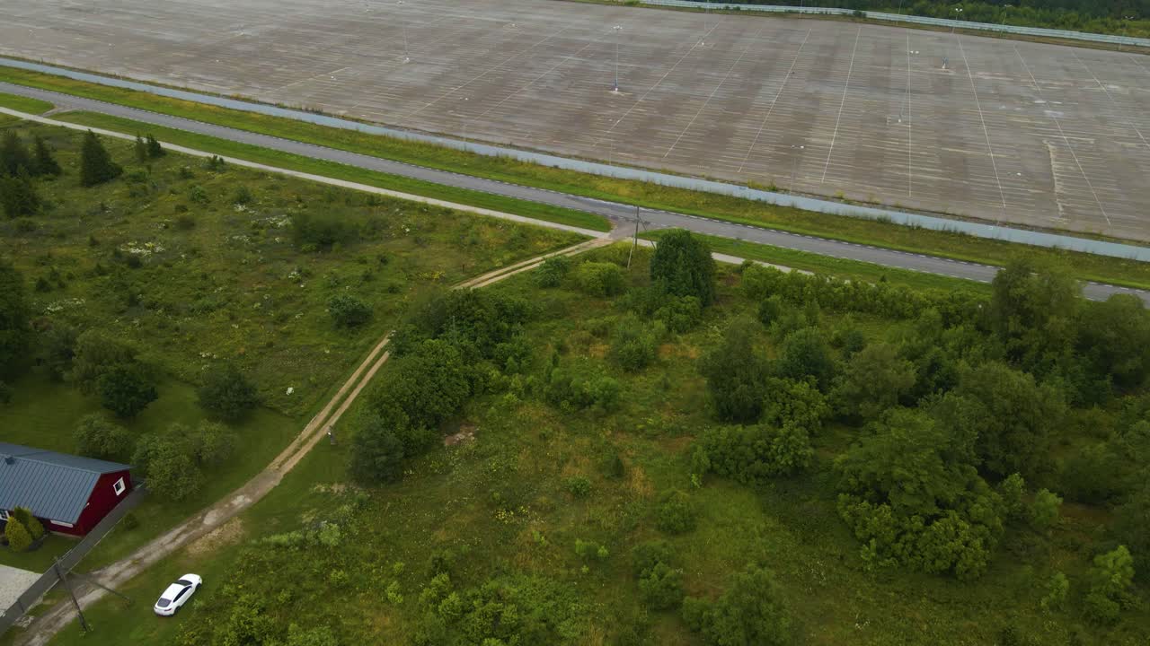 Aerial drone revealing footage flying above a vast empty solar park and showing dozens of white colored renewable energy wind turbines spinning in the background on the cloudy and foggy peninsula