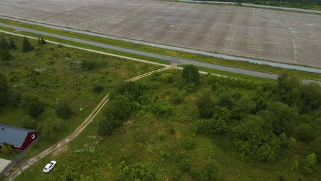 aerial drone revealing footage flying above a vast empty solar park and showing dozens of white colored renewable energy wind turbines spinning in the background on the cloudy and foggy peninsula