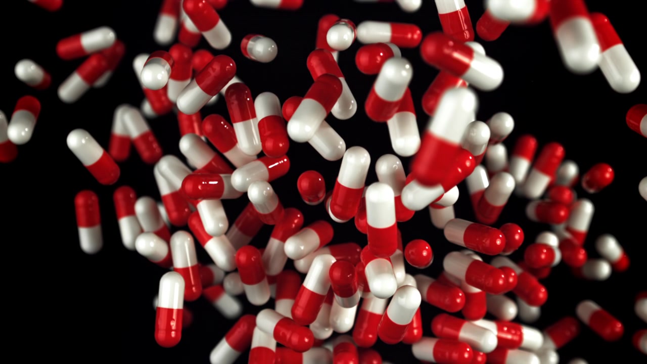 Capsule mediche rosse e bianche che cadono su uno sfondo nero