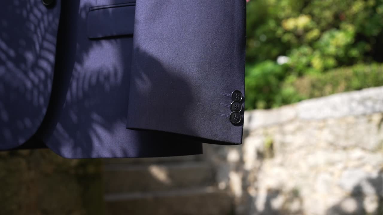 Primo piano di un blazer appeso all'esterno, tra luci e ombre del sole.