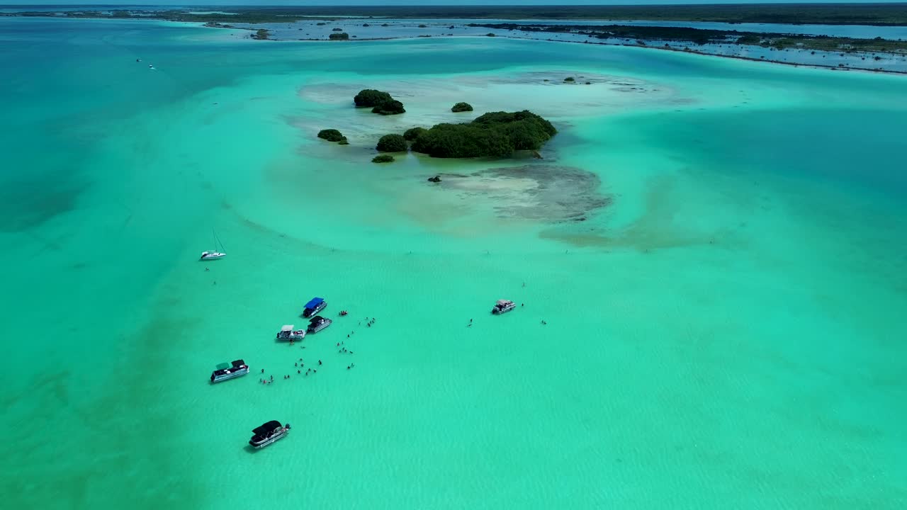 Drone aerial landscape of tourists snorkelling in swim spot with motorboats cruises tour near island swamp with trees Bacalar lagoon lake Mexico travel holidays adventure
