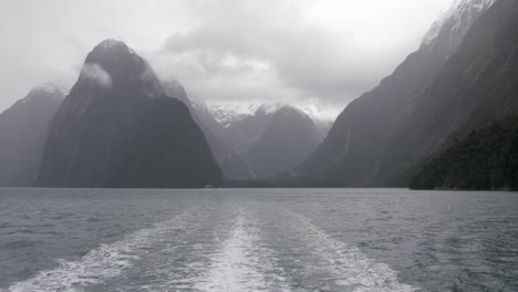 traveling on the beautiful waters of milford sounds in new zealand with mountains kissing the clouds - tilt up