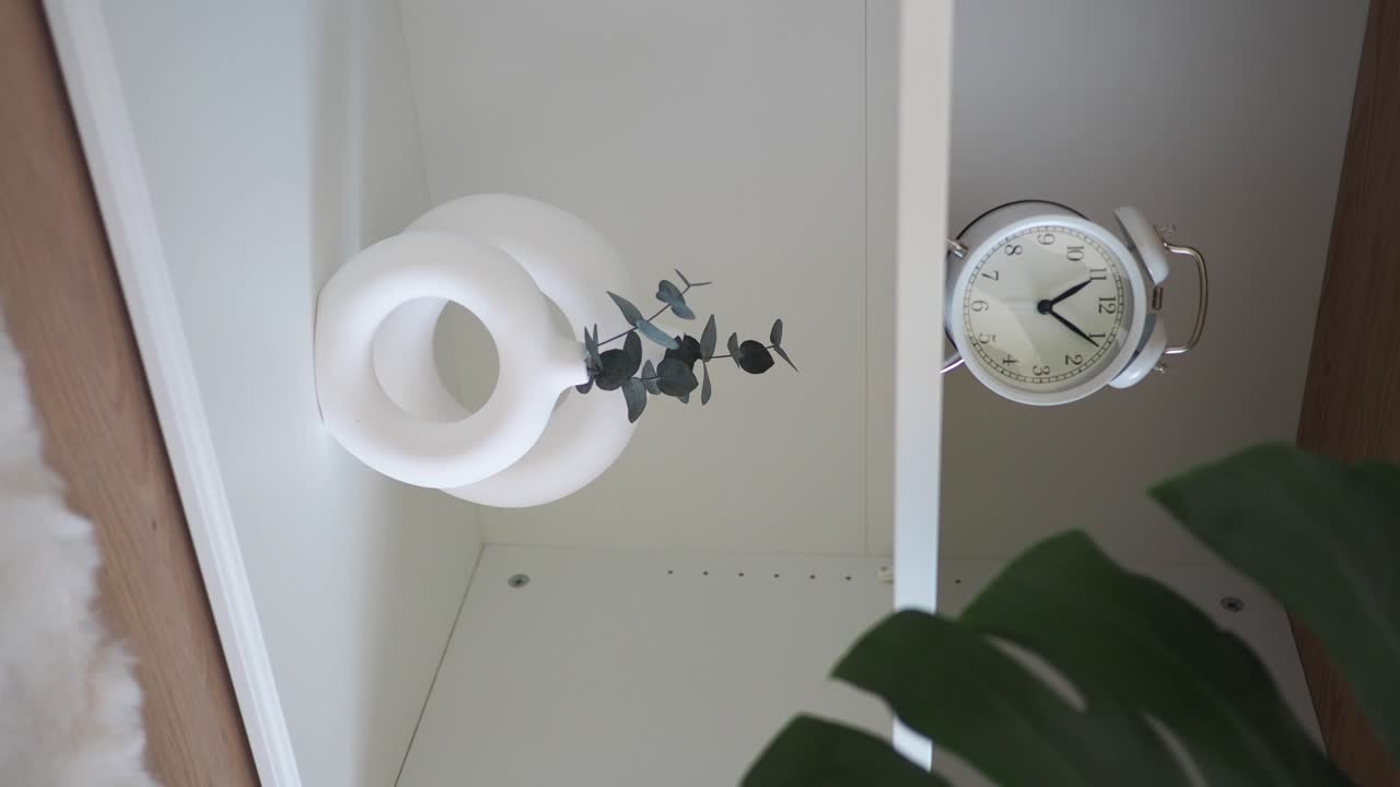 Home decor with clock, vase, and plant on shelf
