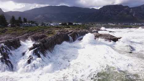 Wütende-Meereswellen-Krachen-In-Die-Felsige-Küste-Und-Erzeugen-Großes-Aufsehen,-Hermanus-Antenne