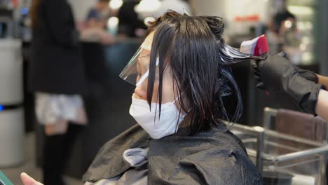 Una-Mujer-Asina-Que-Usa-Una-Máscara-Protectora-De-Virus-Blanco-Mientras-Recibe-Un-Tratamiento-De-Mascarilla-Para-El-Cabello-En-Un-Salón-De-Belleza-En-Corea-Del-Sur-Durante-La-Pandemia-De-Covid-19