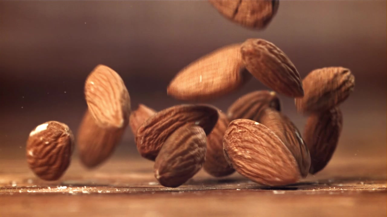 Amandes tombant et rebondissant sur une surface en bois au ralenti.