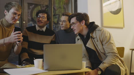 businessman showing information on smartphone to colleagues indoors.