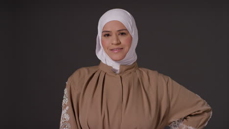 Retrato-De-Estudio-De-Una-Mujer-Musulmana-Sonriente-Usando-Hijab-Contra-Un-Fondo-Oscuro-Y-Liso