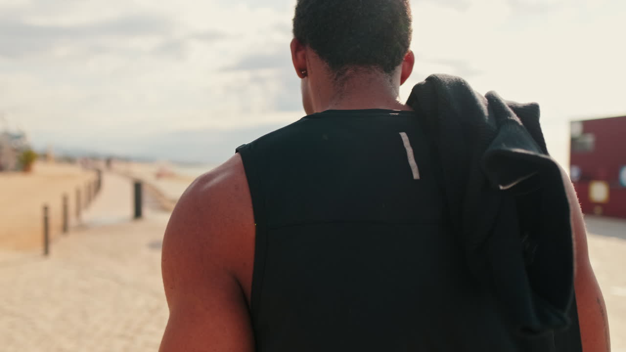 Muscular Man Walks on a Sunny Beach