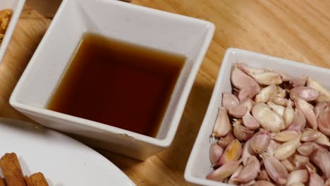 White-Cup-of-Garlic,-Fish-Sauce-and-Coriander-Display-on-Wooden-Tray,-Close-Up