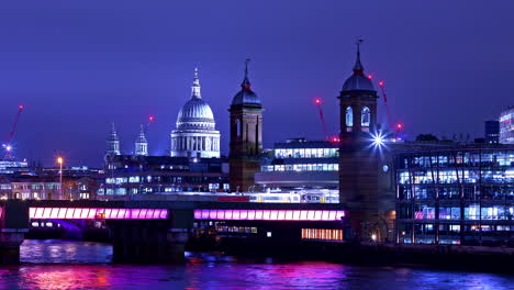 time-lapse of train traffic on cannon street railway bridge over river thames at night time with st