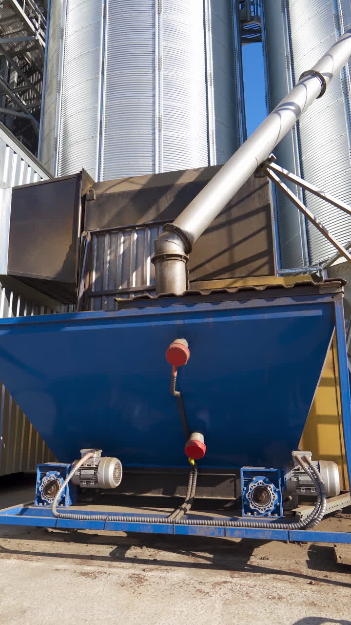 Industrial equipment outdoors. Exterior of modern plant. Large metal grain elevators outdoors. Close-up. Camera moving back. Vertical video