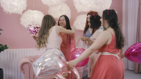 side view of four  women with headdresses jumping and holding ballons