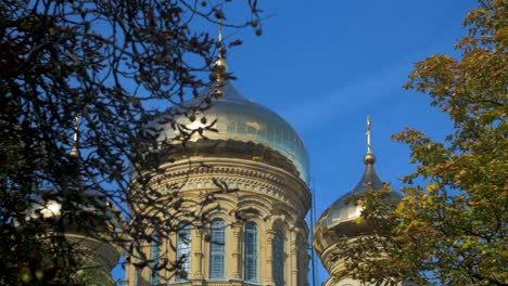 View-of-orthodox-St-Nicholas-Naval-Cathedral-golden-domes-and-crosses-on-blue-sky-in-sunny-autumn-day-at-Karosta,-Liepaja,-pan-right-wide-shot