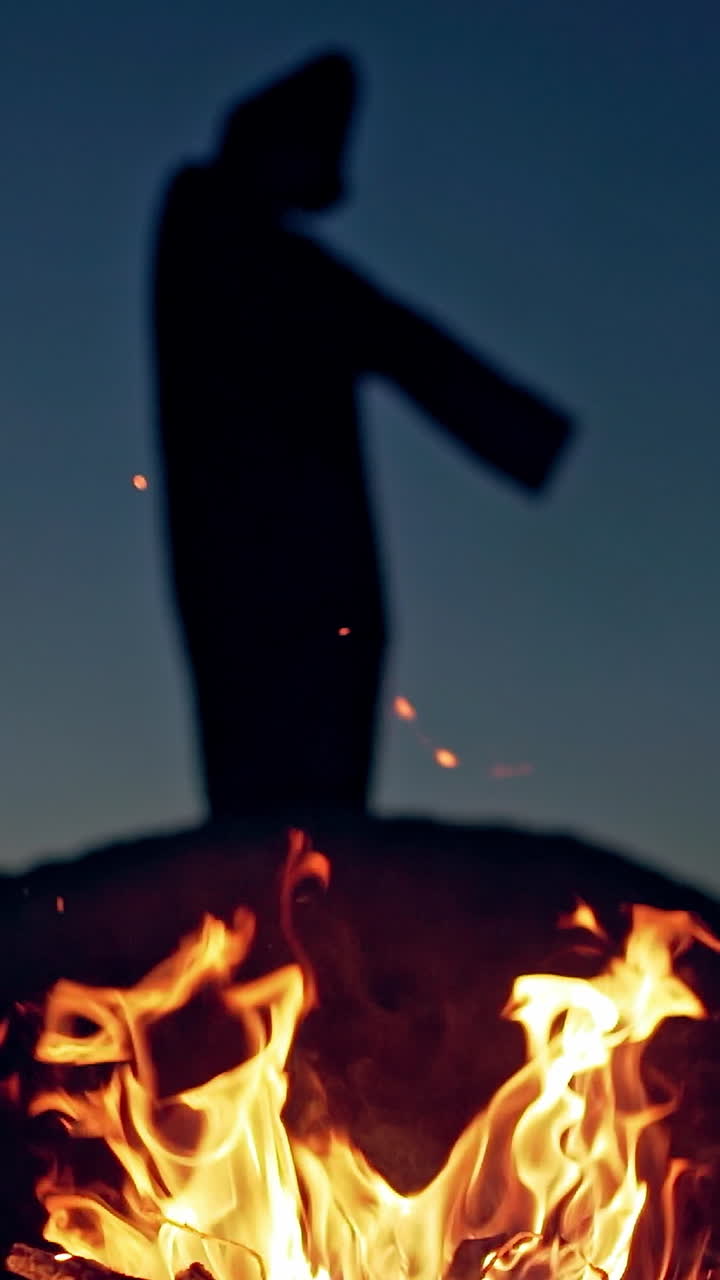 Witch in black near bonfire. Mystical witch walking around bonfire. Vertical video