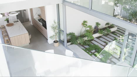 A-modern-kitchen-with-marble-countertops-overlooks-a-small-garden-with-lush-greenery