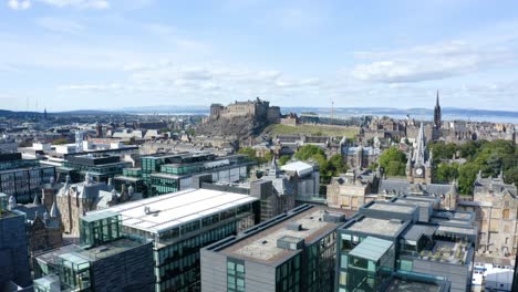 An-epic-aerial-shot-moving-towards-Edinburgh-Castle-over-the-Quartermile-property-development,-on-a-sunny-day