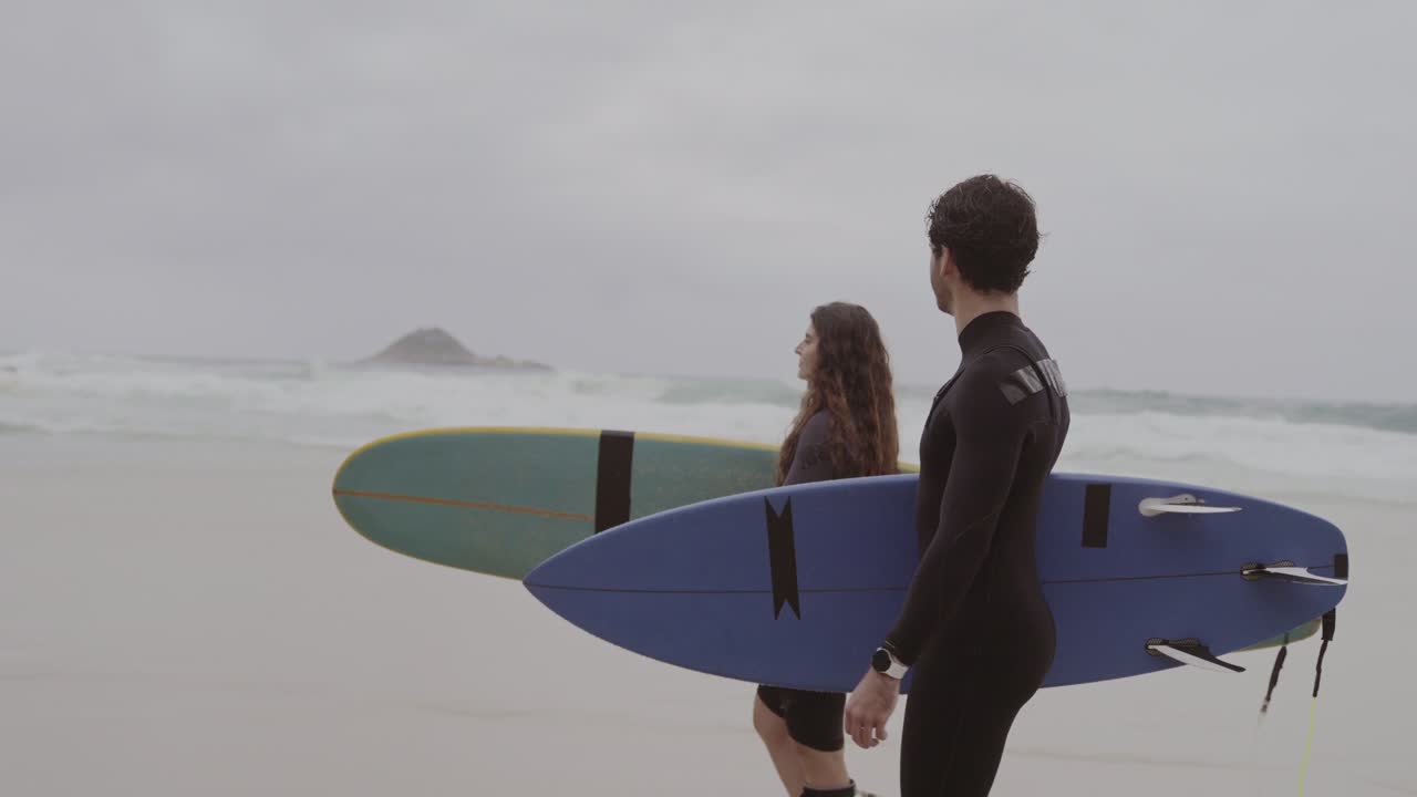 Two surfers walking on a beach with surfboards