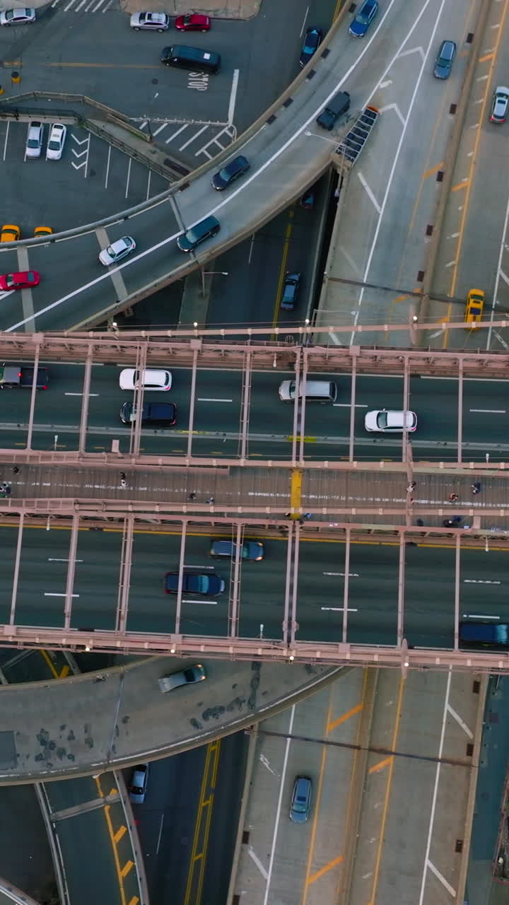 Multiple cars moving quickly over the huge bridge and roads under it. Heavy traffic and car parking lots in a big city. Top view. Vertical video