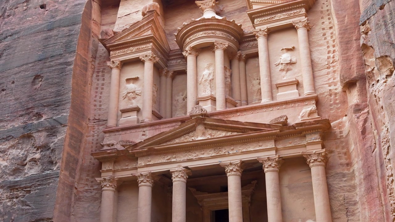 Il Tesoro di Petra rivela la sua facciata in arenaria decorata e le colonne scolpite a Petra, in Giordania, in una ripresa a mano con movimento dal basso verso l'alto