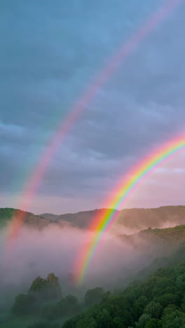 double rainbow over misty mountains