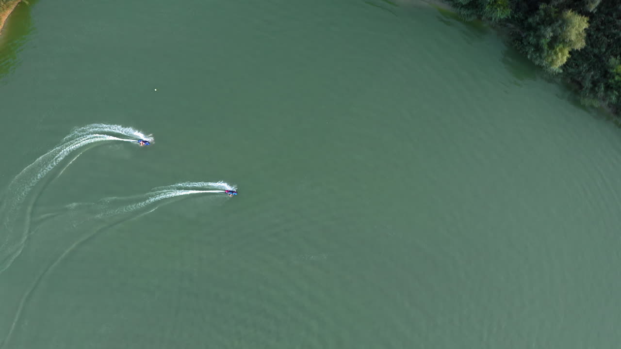 수상 스포츠 휴양지 주변에서 서로 경주하는 제트서핑 보드에 있는 두 사람, 공중 신의 전망