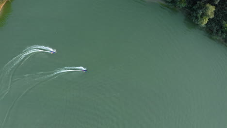 two people on jetsurf boards racing each other around a watersport recreational area, aerial god view