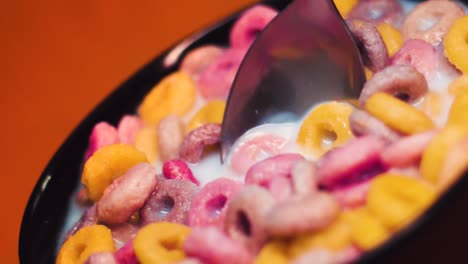 cereales coloridos en un tazón con leche y una cuchara en cámara lenta