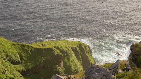 looking down over a cliff in norway at thousands of puffins flying above a rocky coastline, wide angle, slow motion