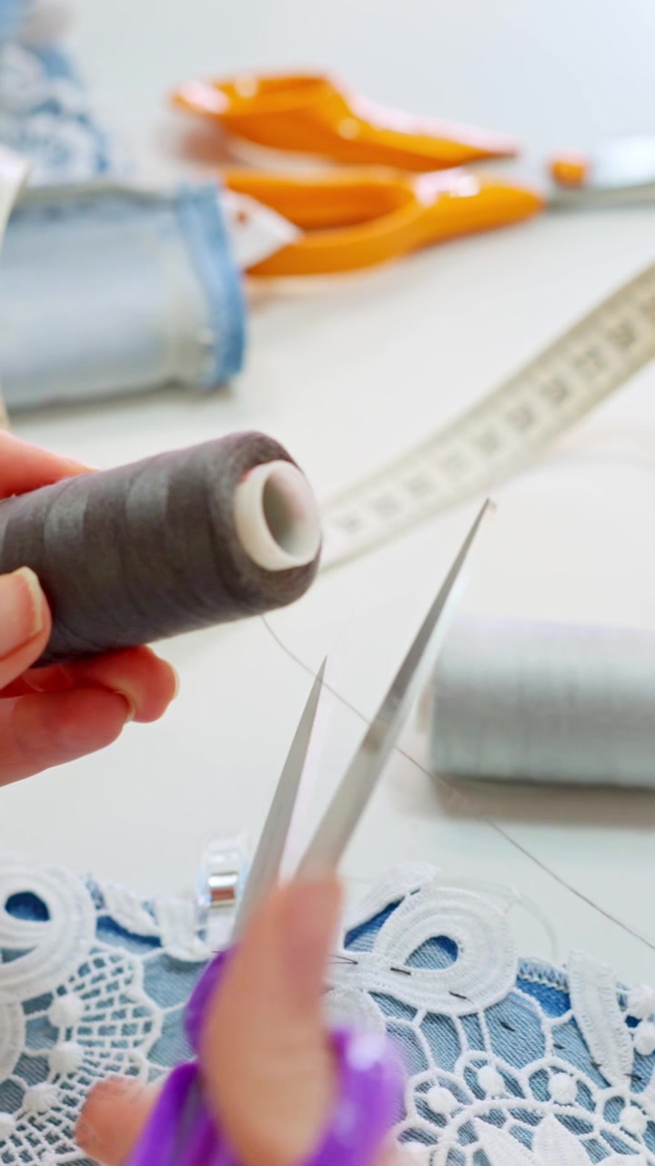 Seamstress hands cutting thread in sewing workshop