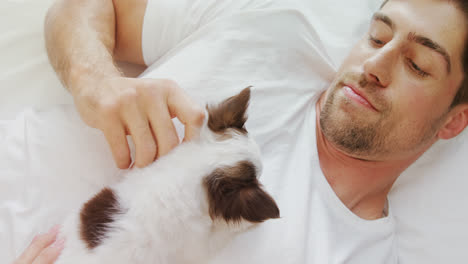 happy young man lying on bed stroking his puppy in the bedroom 4k 4k