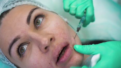 cosmetologist in protective gloves does filler injection