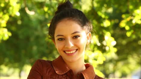 Gorgeous-brunette-walking-towards-the-camera-and-smiling-in-the-park