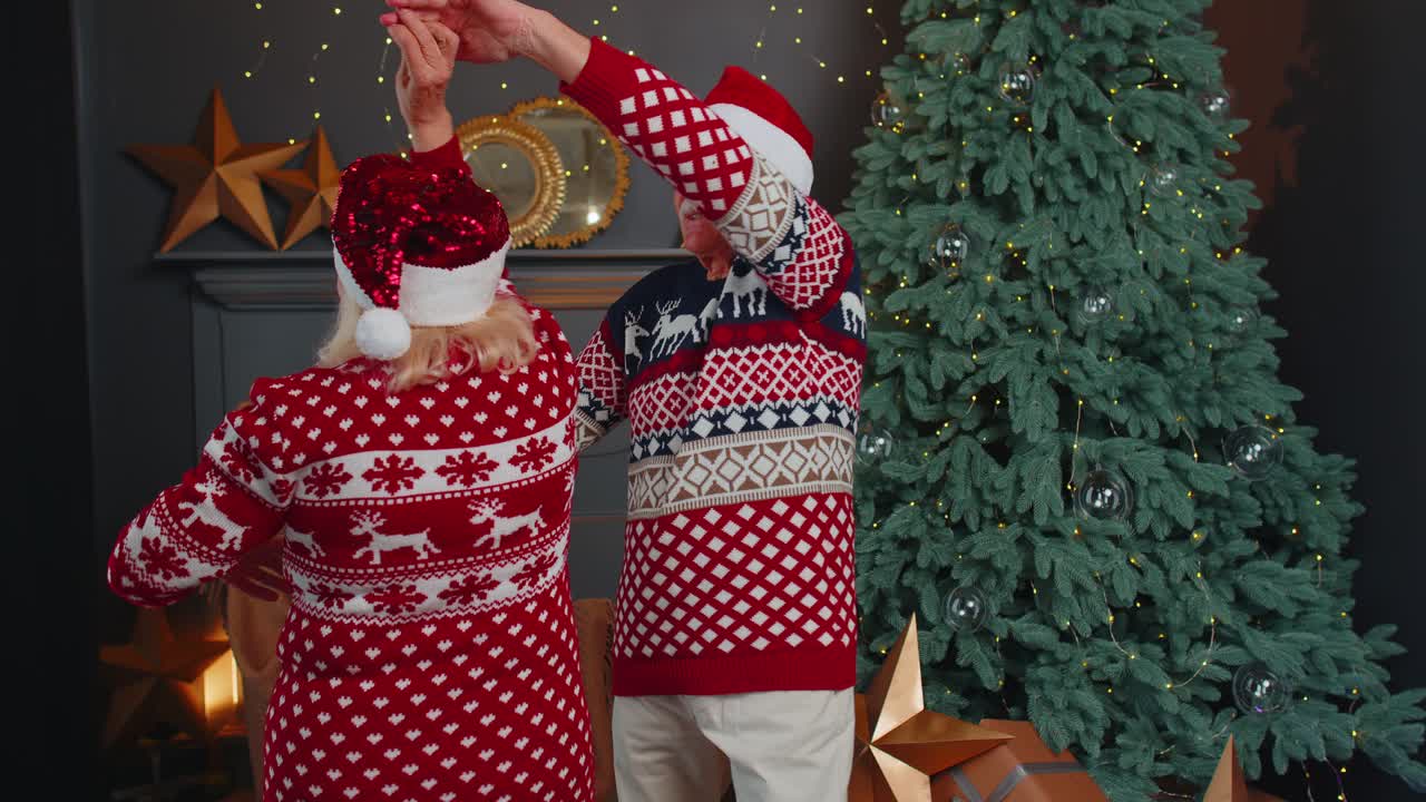만적 인 고령 가족 할아버지와 할머니 부부는 크리스마스 트리 근처에서 집에서 춤을 추고 새해를 축하합니다.