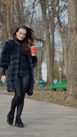 woman walking in a park with coffee