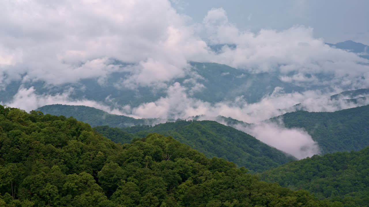 Soft tendrils of cloud collide with mountain fog — cinematic drone pass