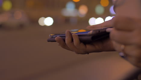 Young-girl-in-evening-street-connects-to-the-mobile-phone-portable-charger